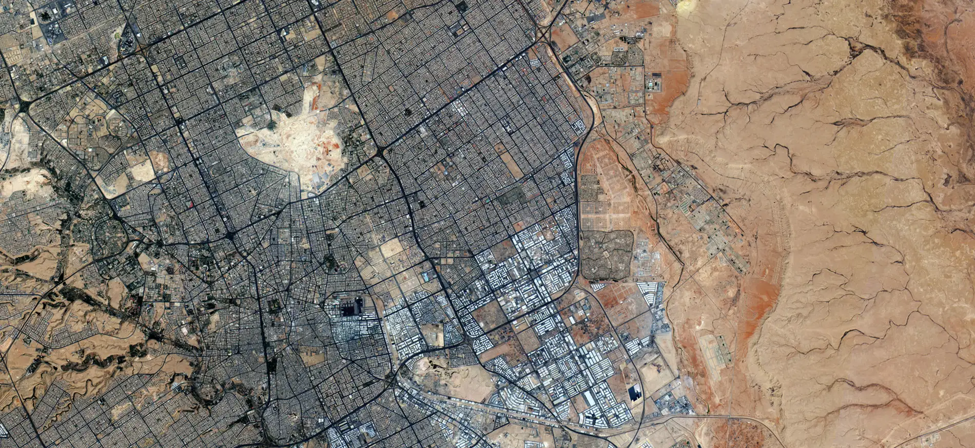 Riyadh photographed from orbit, the city grid meeting the wadi system to the east.